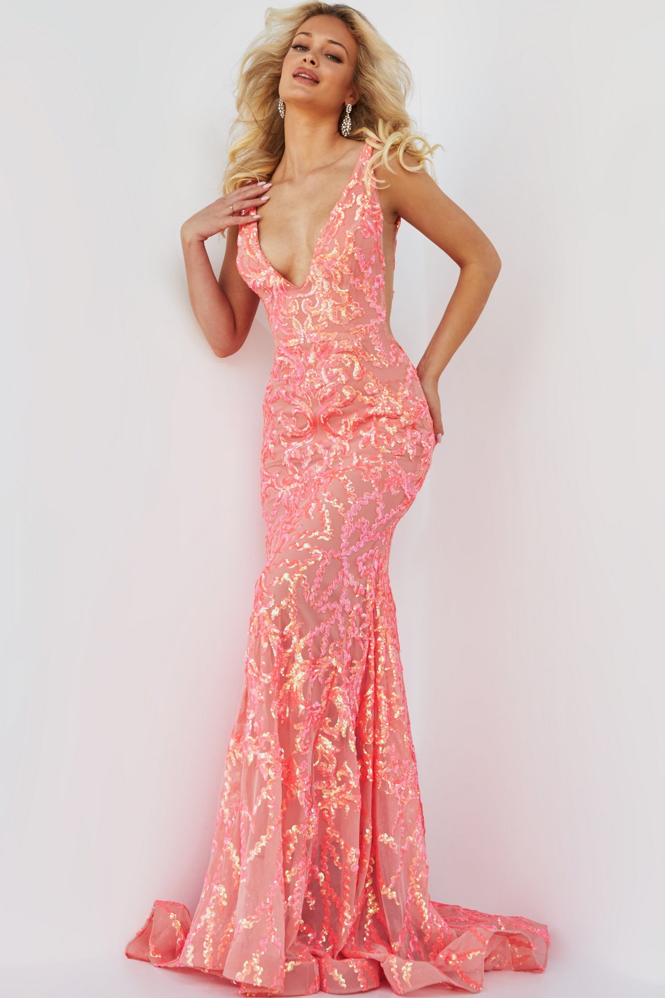 A woman poses in an iridescent coral Jovani Sequin Prom Dress with a plunging neckline and elegant floral sequin embellishments.
